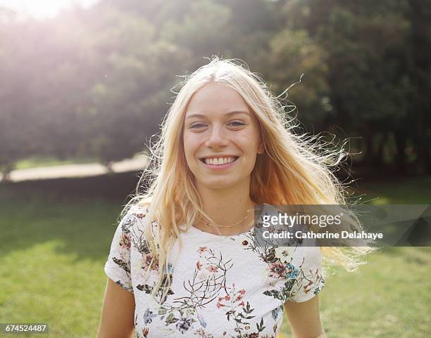 a blond young woman in a park - capelli biondi foto e immagini stock