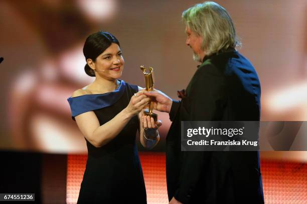 Jasmin Tabatabai, host of the Awards, on stage shaking hands with Tim Pannen who receives the Award for Best Production Design at the Lola - German...