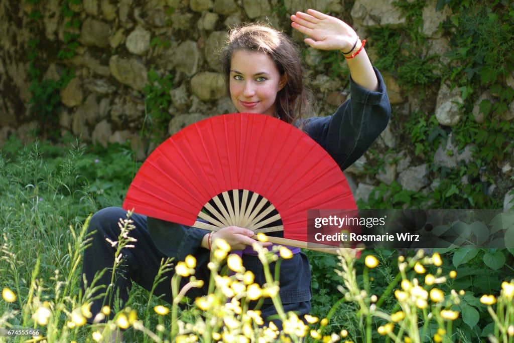 Young woman in kimono holding red fan