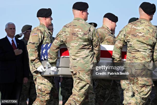 Vice President Mike Pence stands with his hand over his heart as U.S. Army soldiers carry the flag-draped transfer case containing the remains of...