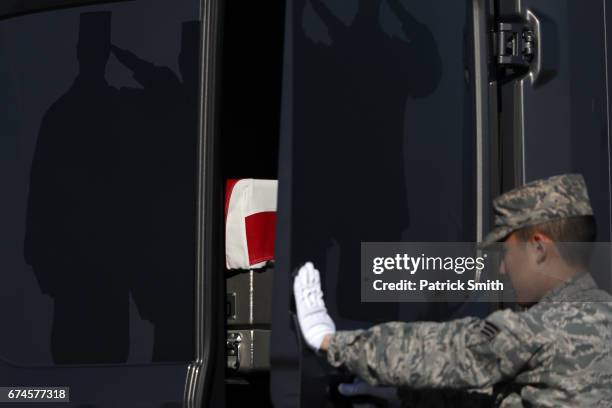 Door Attendant Senior Airman John Lee, Air Force Mortuary Affairs Operations, closes the door of the transfer vehicle as flag-draped transfer cases...