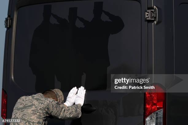 Door Attendant Senior Airman John Lee, Air Force Mortuary Affairs Operations, closes the door of the transfer vehicle as flag-draped transfer cases...