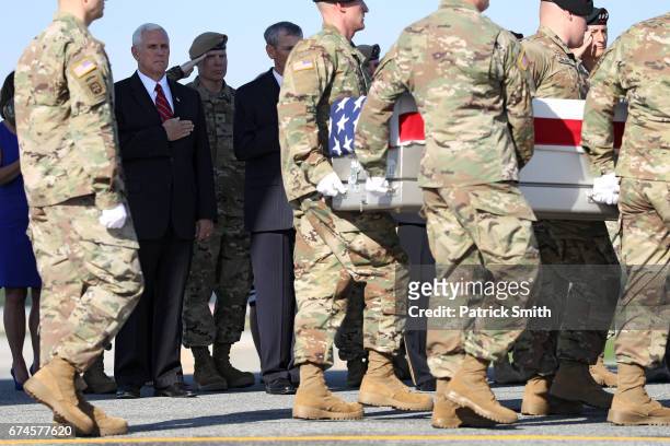 Vice President Mike Pence stands with his hand over his heart as U.S. Army soldiers carry the flag-draped transfer case containing the remains of...