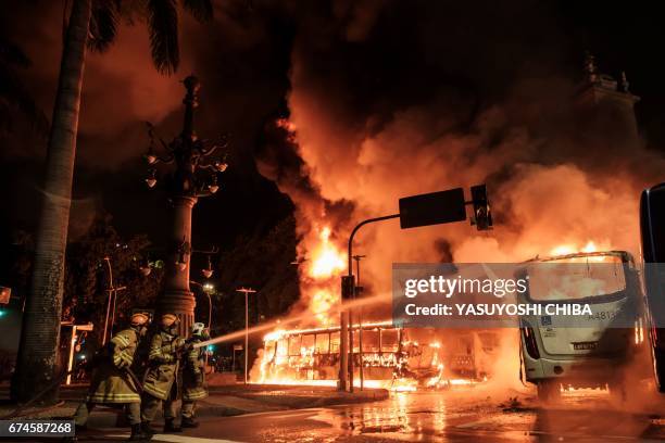 Firefighters try to put out a burning bus set on fire by protesters during the nationwide strike called by unions opposing austerity reforms in Rio...