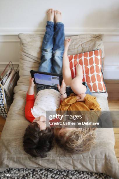 a brother and a sister looking at a tablet - affectueux stock pictures, royalty-free photos & images