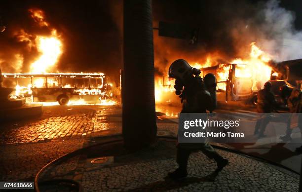 Firefighter walks as buses burn after being set on fire by protestors during a nationwide general strike on April 28, 2017 in Rio de Janeiro, Brazil....