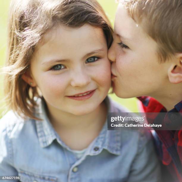 a boy kissing his sister - boy girl kissing stock pictures, royalty-free photos & images