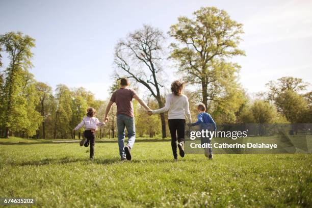 a family running together in a park - running paris stock-fotos und bilder