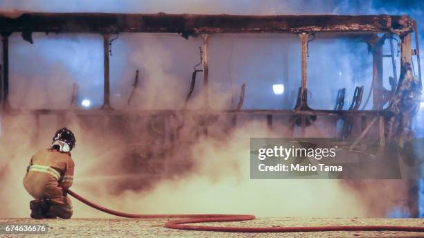 Firefighter works as a bus burns after being set on fire by protestors during a nationwide general strike on April 28, 2017 in Rio de Janeiro,...