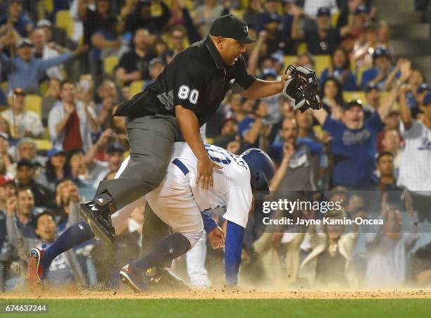 Andrew Toles of the Los Angeles Dodgers collides with umpire Adrian Johnson as he scores on a passed ball by Jerad Eickhoff of the Philadelphia...