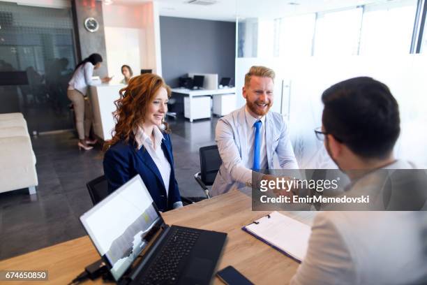 couple talking to loan officer and shaking hands - banking stock pictures, royalty-free photos & images