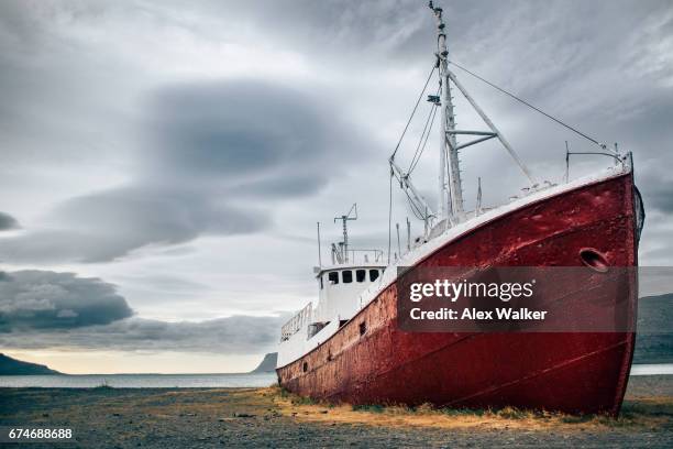 a fishing boat on land in the westfjords, iceland - westfjords iceland stock pictures, royalty-free photos & images