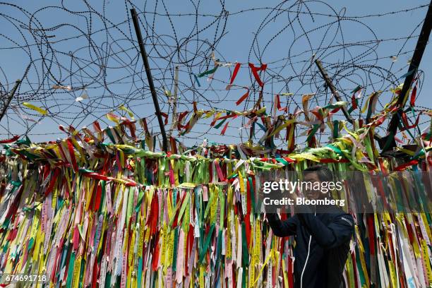 Man takes a photograph of ribbons hanging on a barbed-wire fence at the Imjingak pavilion near the demilitarized zone in Paju, South Korea, on...