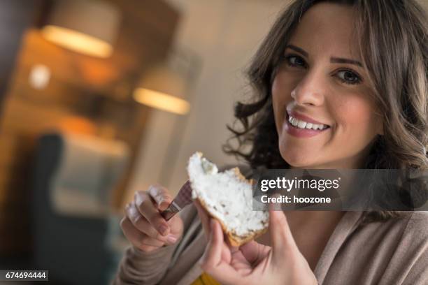 クリーム チーズのパンのスライスの拡散と家で食べる女性 - クリームチーズ ストックフォトと画像
