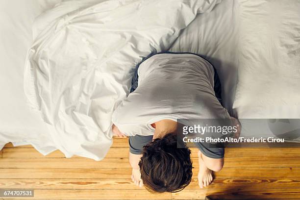 man sitting on edge of bed holding head - bed overhead stock pictures, royalty-free photos & images
