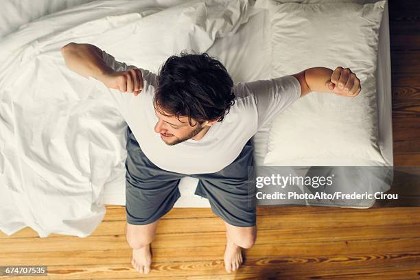 man beginning day with stretches - above view of man sleeping on bed stock pictures, royalty-free photos & images