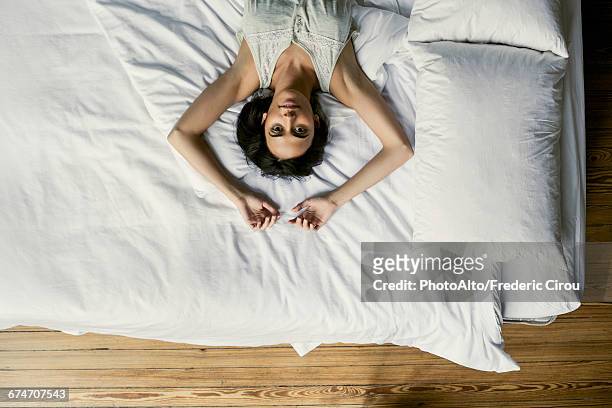 woman lying in bed stretching - reclining stock pictures, royalty-free photos & images
