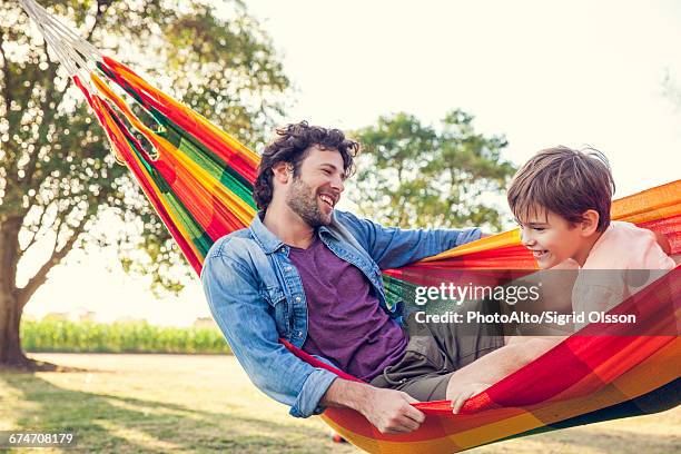 father and son relaxing together in hammock - hammock camping stock pictures, royalty-free photos & images