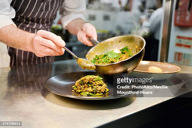 restaurant chef placing cooked lentil dish on plate - franse gerechten stockfoto's en -beelden