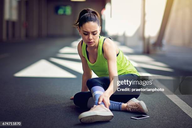 verletzten läufer sitzen auf dem boden mit defekten handy - sports injury stock-fotos und bilder