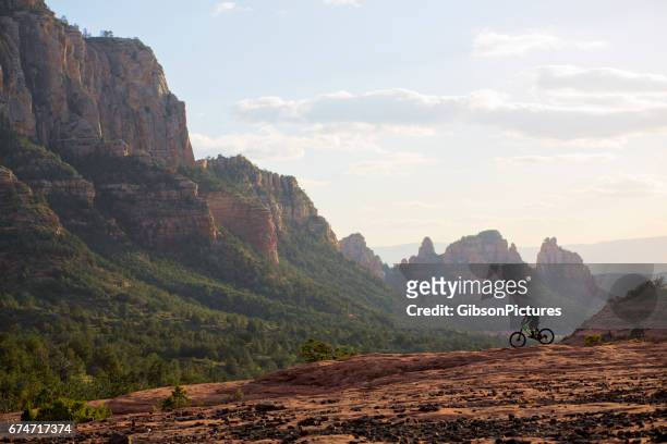 een man rijdt zijn mountainbike enduro-stijl aan het eind van de dag in sedona, arizona, verenigde staten. - arizona mountains stockfoto's en -beelden