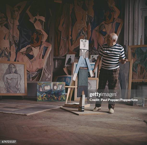 Spanish artist, sculptor and painter, Pablo Picasso pictured smoking a cigarette as he examines one of his sculptures at his house near Cannes in...