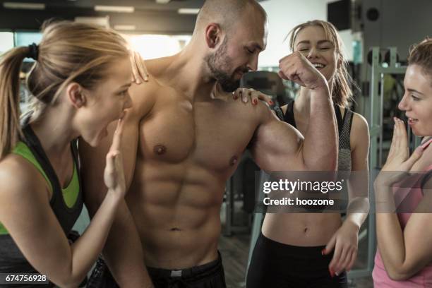 tres mujeres admirando hombres grandes músculos en el gimnasio - presumir fotografías e imágenes de stock