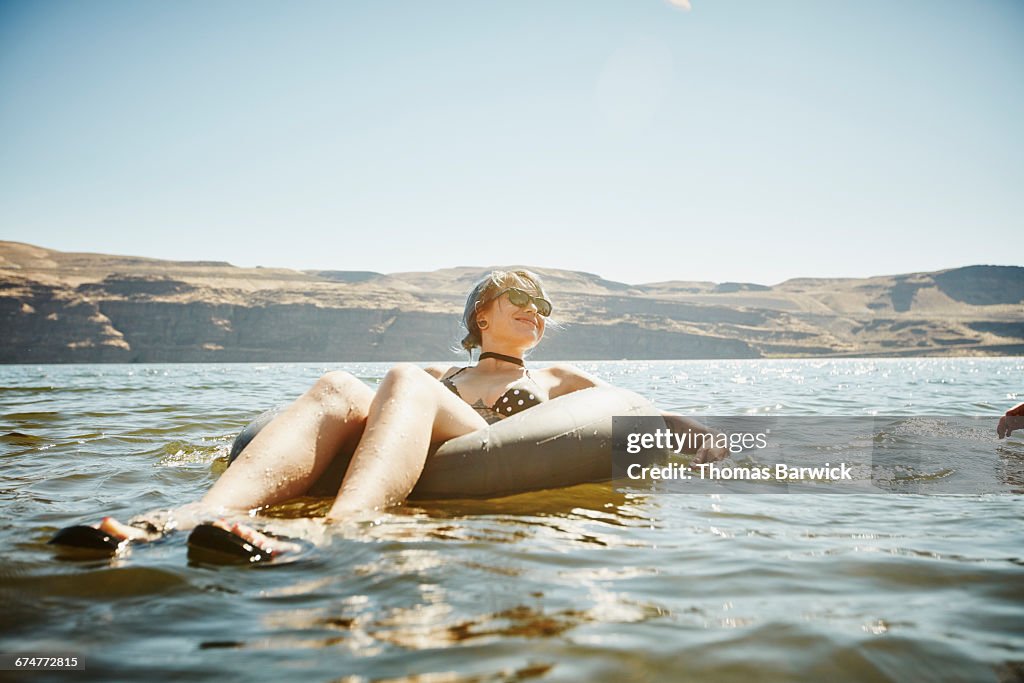 Smiling woman floating in inner tube in river