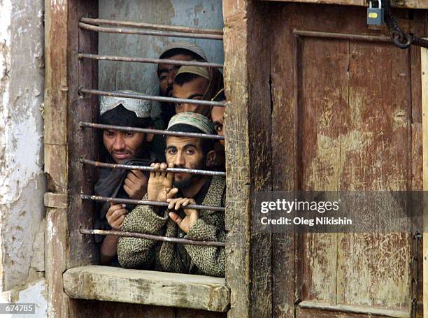 Former Taliban fighters wait inside a cell at a jail complex December 1, 2001 in Shebargan, Afghanistan a week after they surrendered to the Northern...