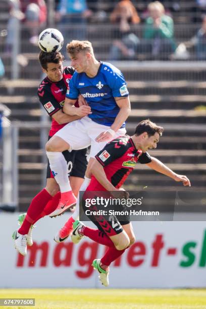 Felix Platte of Darmstadt jumps for a header with Marc-Oliver Kempf and Nicolas Hoefler of Freiburg during the Bundesliga match between SV Darmstadt...