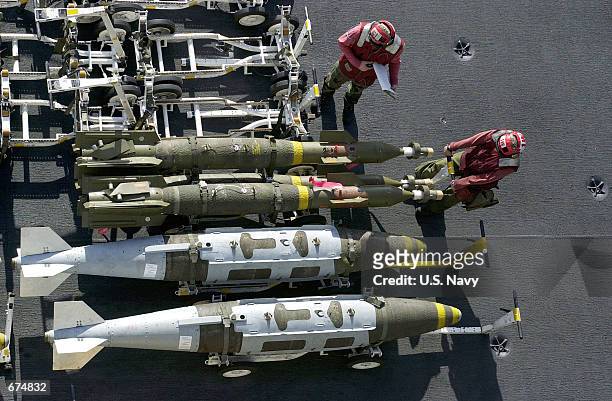 Navy Ordnancemen prepare to move three guided bomb units laser guided bombs parked next to two Joint Direct Attack Munition bombs November 28, 2001...