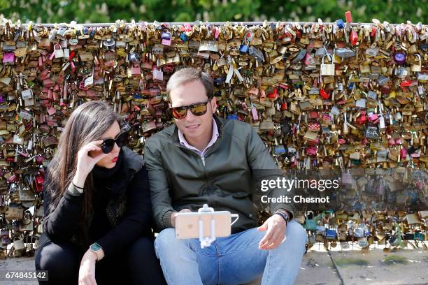 Couple take a selfie in front of Love padlocks on the "Pont Neuf" on April 29, 2017 in Paris, France. The Paris City Hall will organize on May 13th...