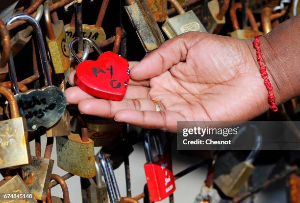 Woman shows a heart-shaped love padlock on the Pont Neuf on April 29, 2017 in Paris, France. The Paris City Hall will organize on May 13th an auction...