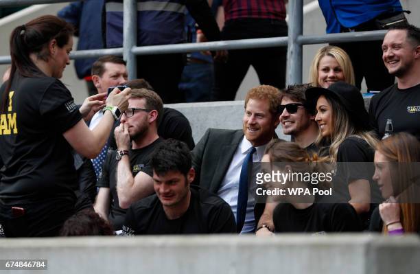 Britain's Prince Harry poses for a picture with competitors from the 2014 and 2016 Invictus Games in the crowd as he watches the annual Army Navy...