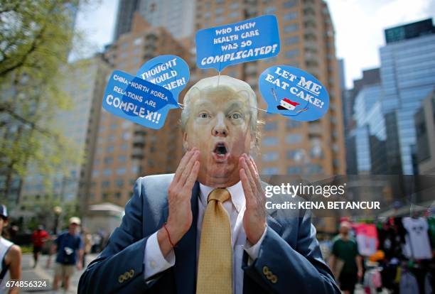 Man wears a mask with the face of US President Donald Trump, as he takes part in the '100 Days of Failure' Protest to mark the first 100 days of the...