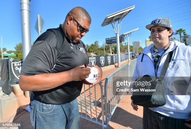 Former Oakland Raiders player Lincoln Kennedy signs a football for a fan during the team's 2017 NFL Draft event at the Welcome to Fabulous Las Vegas...