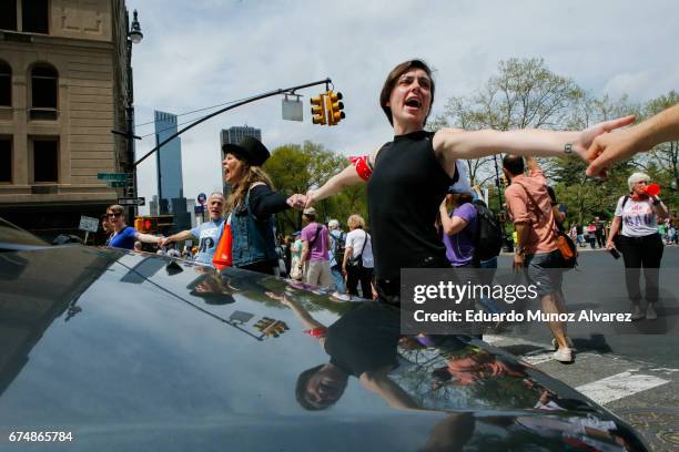 Activists stop traffic as people march against US president Donald Trump in the '100 Days of Failure' protest on April 29, 2017 in New York City....