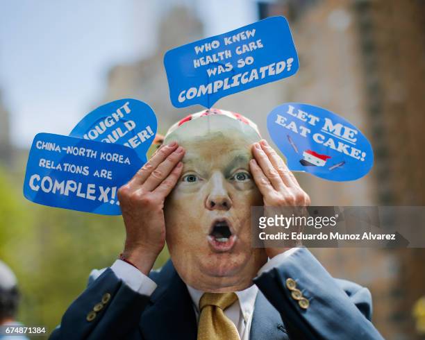 Man wears a mask during the '100 Days of Failure' protest against US President Donald Trump on April 29, 2017 in New York City. Activists are...