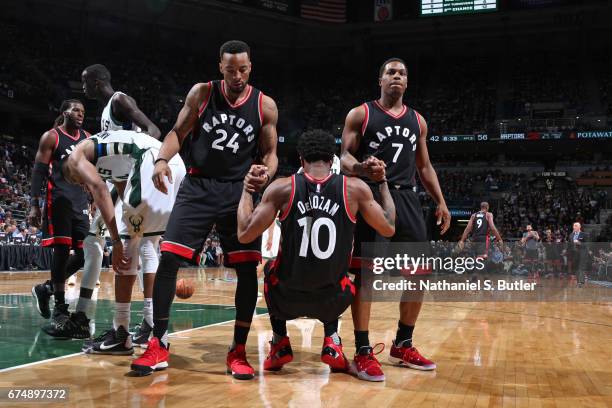 Milwaukee, WI DeMar DeRozan is helped up by teammates Norman Powell and Kyle Lowry of the Toronto Raptors during the game against the Milwaukee Bucks...