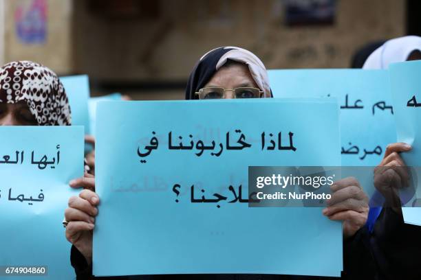 Palestinian women hold placards during a protest demanding end an Israeli blockade of the Gaza Strip, at Al-Shifa hospital in Gaza City on April 29,...