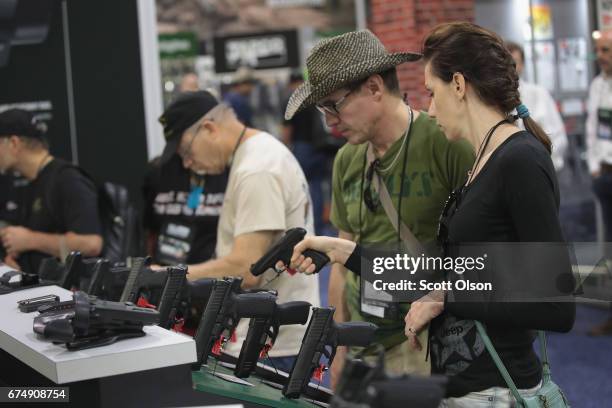 National Rifle Association members look over pistols in the Remington display at the 146th NRA Annual Meetings & Exhibits on April 29, 2017 in...