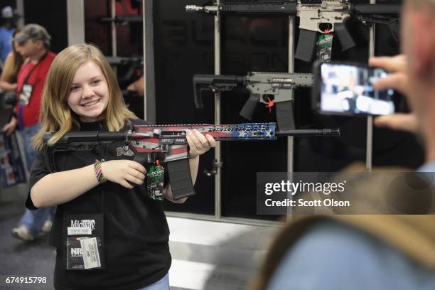 Makenzie Wynn poses for a picture for her father while holding a Black Rain Ordinance rifle at the 146th NRA Annual Meetings & Exhibits on April 29,...