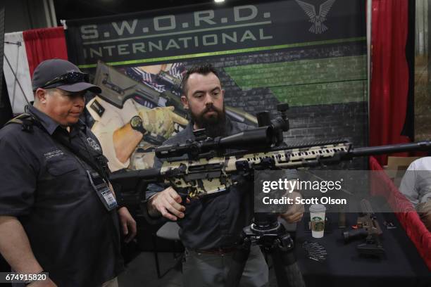 Rus Bacon and Darrin Hall look over a S.W.O.R.D International MK18 model I rifle at the 146th NRA Annual Meetings & Exhibits on April 29, 2017 in...