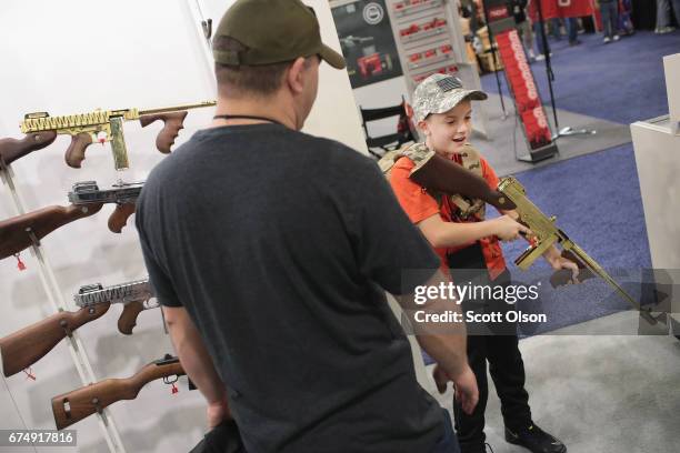 Riley Hathun and his father Steve look over a Thompson rifle at the 146th NRA Annual Meetings & Exhibits on April 29, 2017 in Atlanta, Georgia. With...