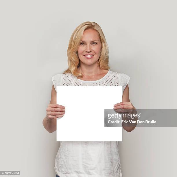 blonde woman holding white card - eric van den brulle stock pictures, royalty-free photos & images