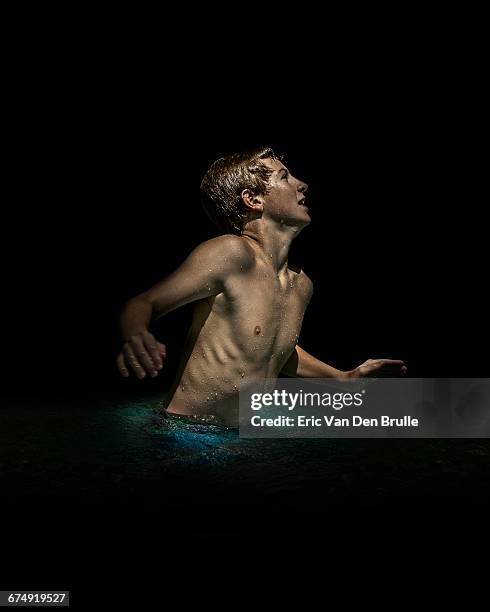 young boy in dark pool of water - eric van den brulle ストックフォトと画像