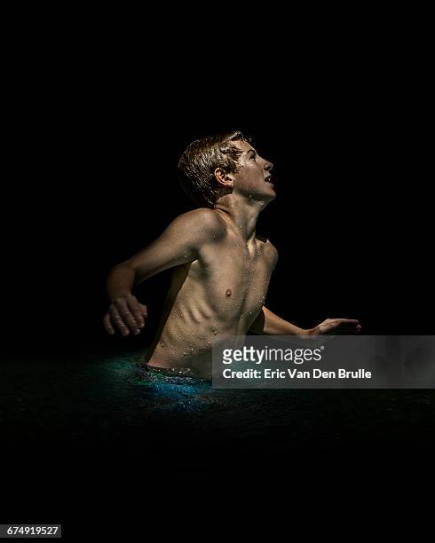 young boy in dark pool of water - eric van den brulle stock pictures, royalty-free photos & images