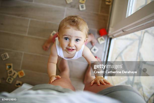 a baby girl holding her mom legs - portrait baby photos et images de collection