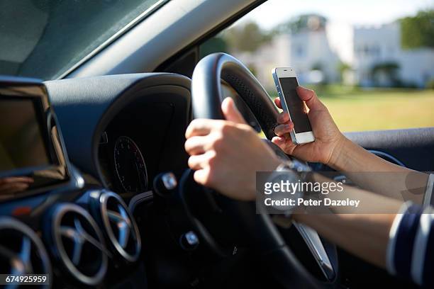 young woman texting while driving - steering wheel stockfoto's en -beelden