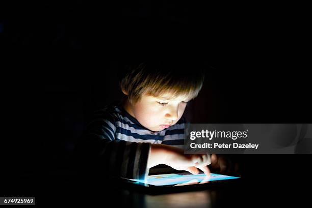 five year old boy on digital tablet at night - children on the internet stock pictures, royalty-free photos & images